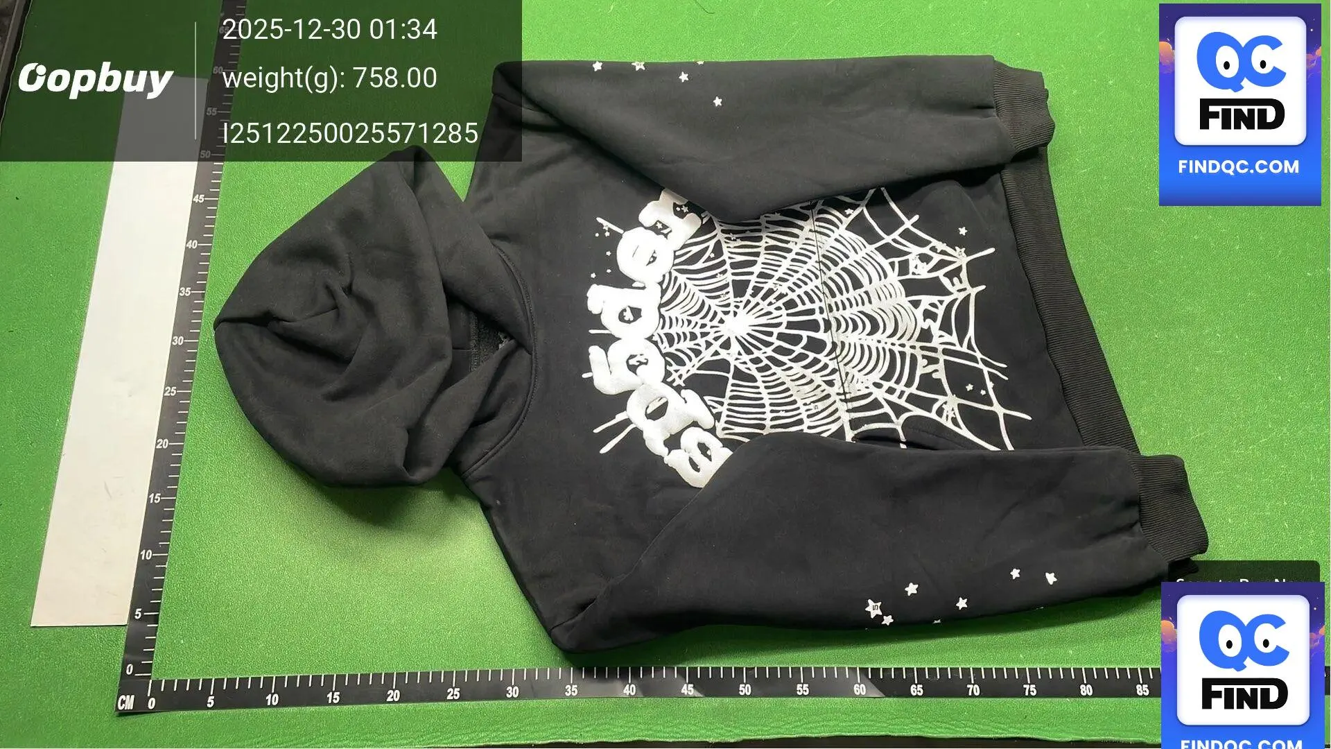 Black graphic hoodie warehouse QC photo on a green inspection mat